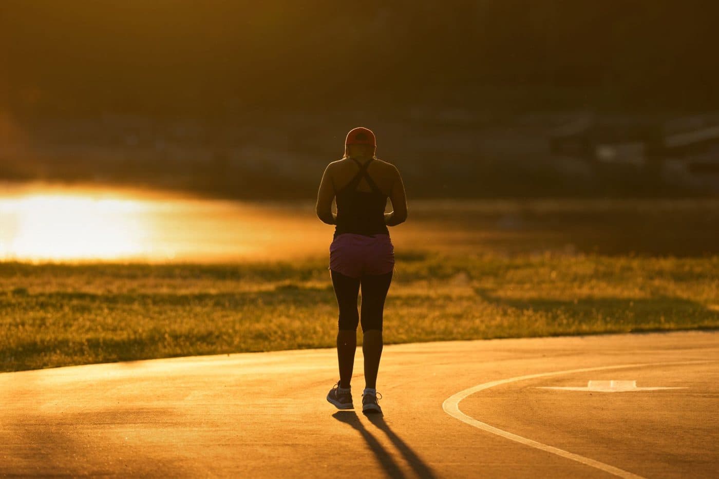 A person walking toward a golden sunrise