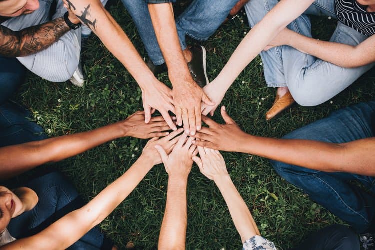 Group members stack their hands together in a show of support