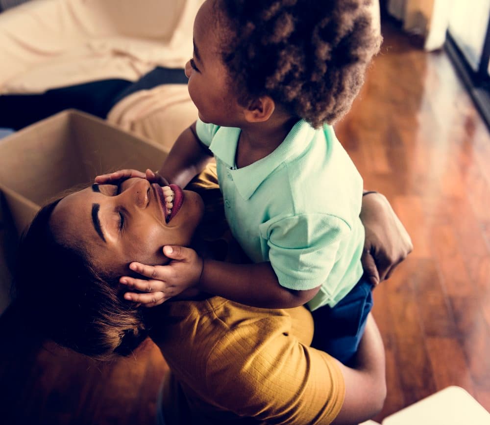 A smiling mother lifting her young son at home